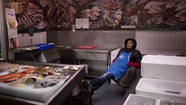 A seller sleeps inside his fish shop as he waits for customers at a market in central Kiev, Ukraine. - Sputnik International