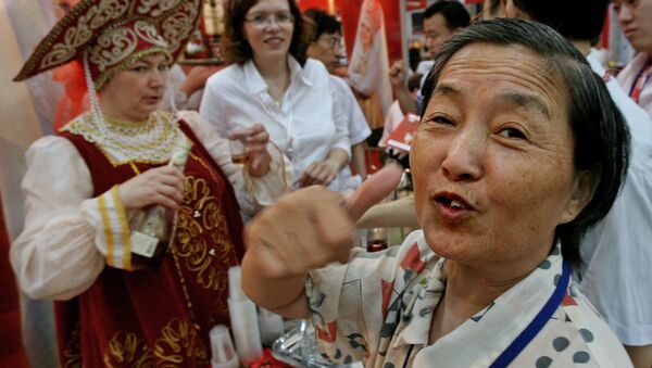 An elderly Chinese woman gives the thumbs up after tasting a vodka from Russia at a trade fair to promote Russian and International food products in Shanghai - Sputnik International