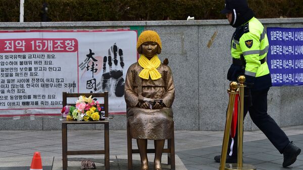 A South Korean policeman walks past a statue (C) of a teenage girl in traditional costume called the peace monument for former comfort women who served as sex slaves for Japanese soldiers during World War II, in front of the Japanese embassy in Seoul on December 29, 2015. - Sputnik International