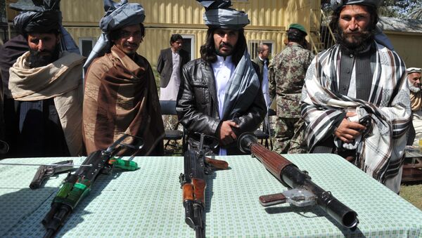 Former Taliban fighters look on as they stand alongside their weapons in Jalalabad, the capital of Nangarhar province on March 19, 2014 - Sputnik International