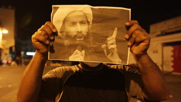 Bahraini anti-government protester holds up a picture of jailed Saudi Sheik Nimr al-Nimr during clashes with riot police in Sanabis, Bahrain, a suburb of the capital Manama - Sputnik International