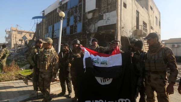 Iraqi security forces place the Iraqi flag above the Islamic State group flag as they pose for a picture on December 28, 2015 in front of the Anbar police headquarters after they recaptured the city of Ramadi, the capital of Iraq's Anbar province, about 110 kilometers west of Baghdad - Sputnik International