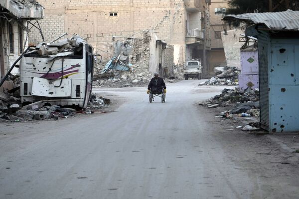 A man propels his wheelchair on February 13, 2014 in a devastated street in the Syrian eastern town of Deir Ezzor - Sputnik International