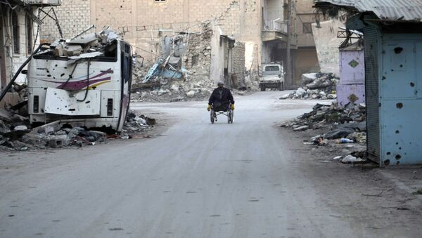 A man propels his wheelchair on February 13, 2014 in a devastated street in the Syrian eastern town of Deir Ezzor - Sputnik International