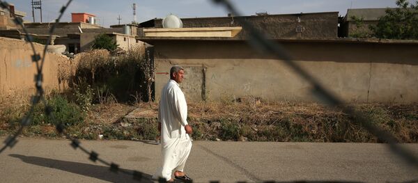 In this Wednesday, May 27, 2015 photo, a resident of Eski Mosul, Iraq is seen through barbed wire while passing the former base of the Islamic State group in the town while it was under the militants' control In this Wednesday, May 27, 2015 photo, a resident of Eski Mosul, Iraq is seen through barbed wire while passing the former base of the Islamic State group in the town while it was under the militants' control - Sputnik International