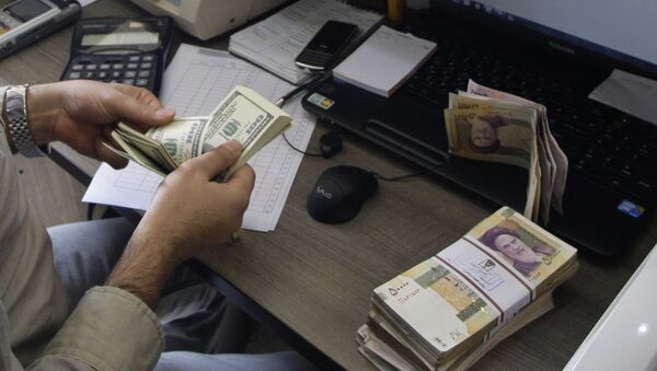 A currency exchange bureau worker counts US dollars, as Iranian bank notes are seen at right with portrait of late revolutionary founder Ayatollah Khomeini. - Sputnik International