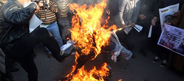 Followers of Shiite cleric Muqtada al-Sadr burn an effigy of King Salman of Saudi Arabia as they hold posters of Sheik Nimr al-Nimr during a demonstration in Baghdad, Iraq. - Sputnik International