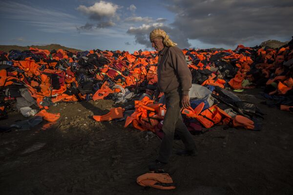 A man walks across piles of life jackets used by refugees and migrants to cross the Aegean sea from the Turkish coast which remained stacked on the Greek eastern island of Lesbos, Wednesday, Dec. 2, 2015. A man walks across piles of life jackets used by refugees and migrants to cross the Aegean sea from the Turkish coast which remained stacked on the Greek eastern island of Lesbos, Wednesday, Dec. 2, 2015. - Sputnik International