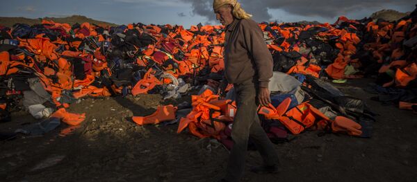 A man walks across piles of life jackets used by refugees and migrants to cross the Aegean sea from the Turkish coast which remained stacked on the Greek eastern island of Lesbos, Wednesday, Dec. 2, 2015. A man walks across piles of life jackets used by refugees and migrants to cross the Aegean sea from the Turkish coast which remained stacked on the Greek eastern island of Lesbos, Wednesday, Dec. 2, 2015. - Sputnik International