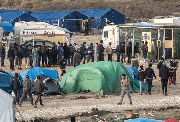 People walk at the migrant camp known as the Jungle in Calais on December 7, 2015 People walk at the migrant camp known as the Jungle in Calais on December 7, 2015 - Sputnik International