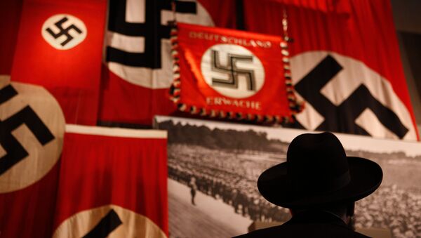 A man looks at exhibit showing the Nazi flags. - Sputnik International