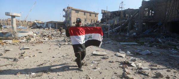 A member of the Iraqi security forces holds his national flag on December 28, 2015 at the heavily damaged government complex after they recaptured the city of Ramadi, the capital of Iraq's Anbar province, about 110 kilometers west of Baghdad, from Islamic States group jihadists - Sputnik International