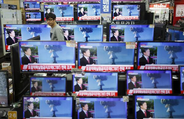 A sales assistant watches TV sets broadcasting a news report on North Korea's nuclear test, in Seoul, January 6, 2016 - Sputnik International