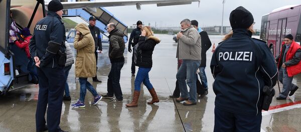 Police officers escort rejected refugees who are boarding an aircraft at the airfield of the Franz-Josef-Strauss airport in Munich, southern Germany, on December 9, 2015, as the plane brings rejected asylum seekers back to their country - Sputnik International