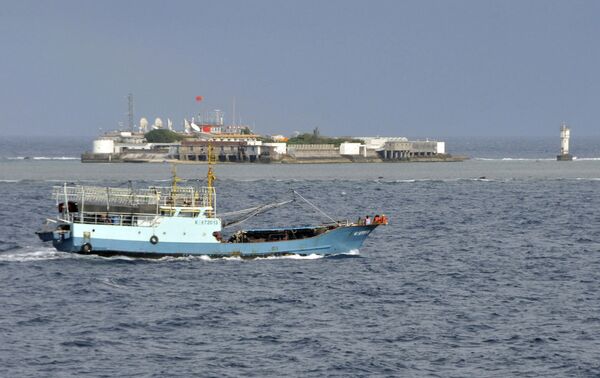 Chinese fishing vessel sails by Fiery Cross Reef, background, also known as Yongshu Reef by the Chinese, of the Spratly Islands in the South China Sea Chinese fishing vessel sails by Fiery Cross Reef, background, also known as Yongshu Reef by the Chinese, of the Spratly Islands in the South China Sea - Sputnik International