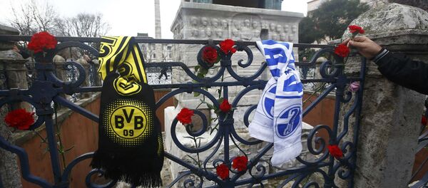 A man places a flower next to German football club scarves at the Obelisk of Theodosius, the scene of the suicide bomb attack, at Sultanahmet square in Istanbul, Turkey - Sputnik International