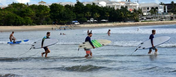 Foreign tourists hold surf boards as they wade into the waters off Kuta beach, Bali island Foreign tourists hold surf boards as they wade into the waters off Kuta beach, Bali island - Sputnik International