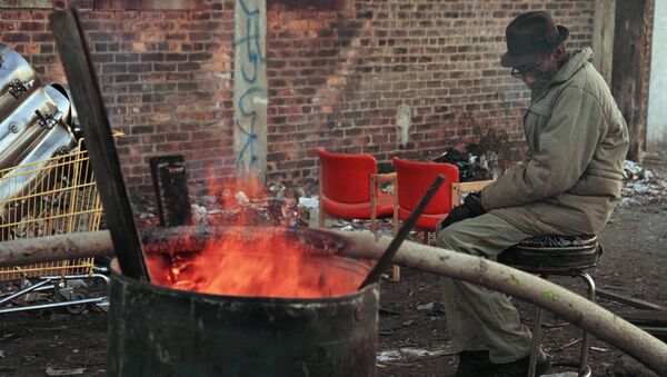 A homeless man sits by a barrel fire to keep warm near downtown Detroit. (File) - Sputnik International