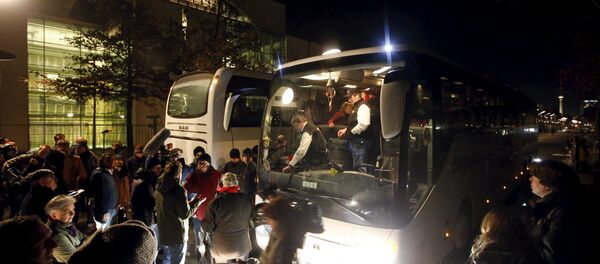 A bus (R) with refugees from the Bavarian town of Landshut is pictured after its arrival to the Chancellery building in Berlin, Germany, January 14, 2016 - Sputnik International
