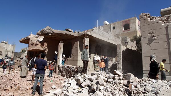 Yemeni men walk past a building, damaged during an air-strike by the Saudi-led coalition, in the capital Sanaa on November 29, 2015 - Sputnik International