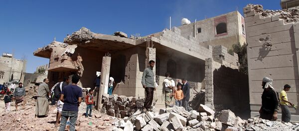 Yemeni men walk past a building, damaged during an air-strike by the Saudi-led coalition, in the capital Sanaa on November 29, 2015 - Sputnik International
