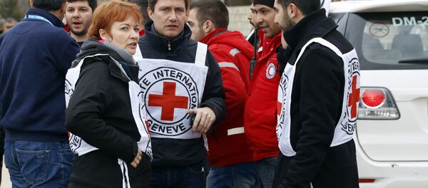 In this Monday, Jan. 11, 2016 photo, aid workers stand near a convoy of vehicles loaded with food and other supplies organized by the International Committee of the Red Cross, working alongside the Syrian Arab Red Crescent and the United Nations, makes it's way to the besieged town of Madaya, about 15 miles (24 kilometers) northwest of Damascus, Syria In this Monday, Jan. 11, 2016 photo, aid workers stand near a convoy of vehicles loaded with food and other supplies organized by the International Committee of the Red Cross, working alongside the Syrian Arab Red Crescent and the United Nations, makes it's way to the besieged town of Madaya, about 15 miles (24 kilometers) northwest of Damascus, Syria - Sputnik International