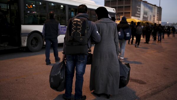 A Syrian refugee couple carry their belongings as refugees and migrants arrive aboard the passenger ferry Nissos Rodos at the port of Piraeus, near Athens, Greece, January 13, 2016 - Sputnik International