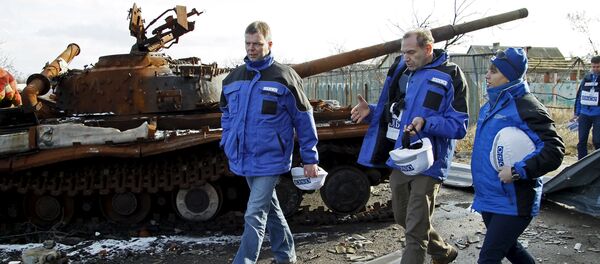 Deputy Chief of the OSCE's Special Monitoring Mission to Ukraine Alexander Hug (L), with members of the mission, walks past a burnt tank as he inspects an area between DPR forces and Ukrainian government troops in the village of Kominternove north-east of the port city of Mariupol, Ukraine, January 15, 2016 - Sputnik International