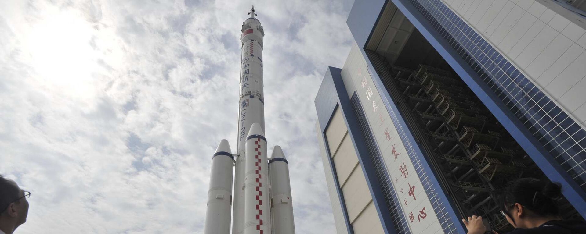 This file photo taken on September 20, 2008 shows Chinese tourists gathering to watch the Shenzhou-7 manned spaceship on top of the Long-March II-F rocket being transfered to the launchpad at the Jiuquan Satellite Launch Center in northwest China's Gansu province - Sputnik International, 1920, 25.07.2023
