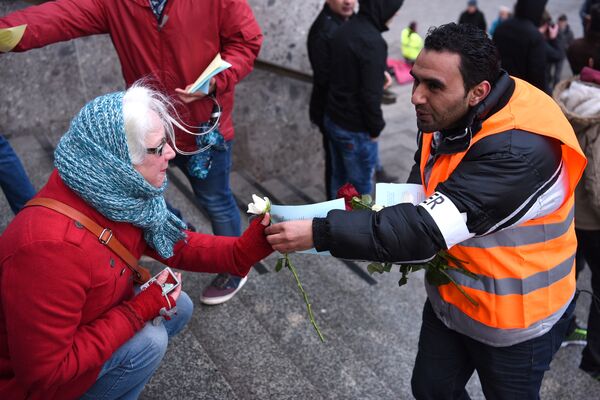 Refugees from Syria present flowers to passers-by as they demonstrate against violence near the Cologne main train station in Cologne, western Germany on January 16, 2016, where hundreds of women were groped and robbed in a throng of mostly Arab and North African men during New Year's festivities Refugees from Syria present flowers to passers-by as they demonstrate against violence near the Cologne main train station in Cologne, western Germany on January 16, 2016, where hundreds of women were groped and robbed in a throng of mostly Arab and North African men during New Year's festivities - Sputnik International