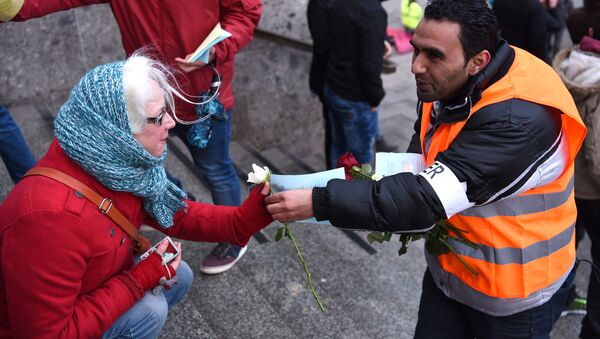 Refugees from Syria present flowers to passers-by as they demonstrate against violence near the Cologne main train station in Cologne, western Germany on January 16, 2016, where hundreds of women were groped and robbed in a throng of mostly Arab and North African men during New Year's festivities - Sputnik International