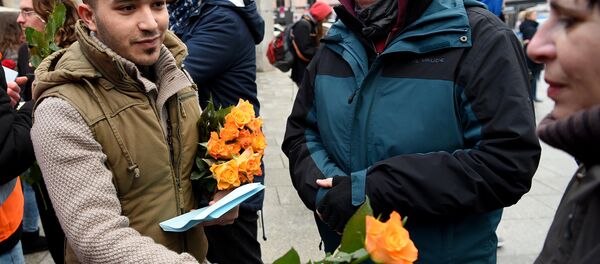 Refugees from Syria present flowers to passers-by as they demonstrate against violence near the Cologne main train station in Cologne, western Germany on January 16, 2016, where hundreds of women were groped and robbed in a throng of mostly Arab and North African men during New Year's festivities Refugees from Syria present flowers to passers-by as they demonstrate against violence near the Cologne main train station in Cologne, western Germany on January 16, 2016, where hundreds of women were groped and robbed in a throng of mostly Arab and North African men during New Year's festivities - Sputnik International