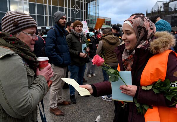 Refugees from Syria present flowers to passers-by as they demonstrate against violence near the Cologne main train station in Cologne, western Germany on January 16, 2016, where hundreds of women were groped and robbed in a throng of mostly Arab and North African men during New Year's festivities Refugees from Syria present flowers to passers-by as they demonstrate against violence near the Cologne main train station in Cologne, western Germany on January 16, 2016, where hundreds of women were groped and robbed in a throng of mostly Arab and North African men during New Year's festivities - Sputnik International