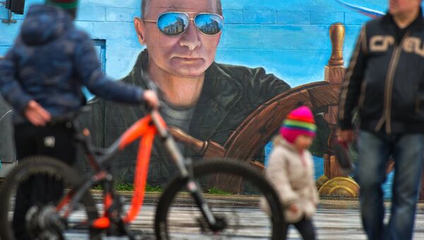 Pedestrians near a portrait of Russian President Vladimir Puitn on a wall of a building in Yalta - Sputnik International