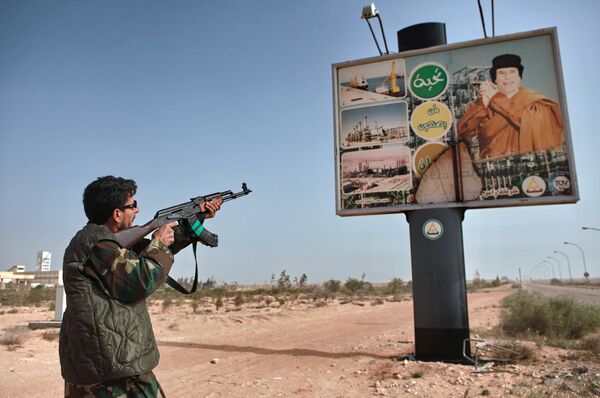 An armed supporter of the Libyan opposition shoots a machine gun at a poster with the image of Muhammar Gaddafi in the captured rebel town of Ras-Lanuf in the east of the country An armed supporter of the Libyan opposition shoots a machine gun at a poster with the image of Muhammar Gaddafi in the captured rebel town of Ras-Lanuf in the east of the country - Sputnik International