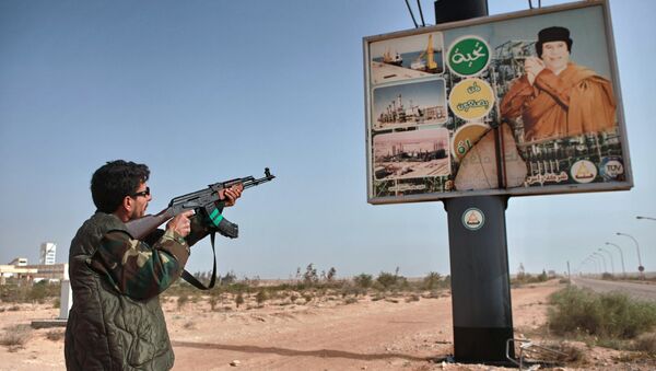 An armed supporter of the Libyan opposition shoots a machine gun at a poster with the image of Muhammar Gaddafi in the captured rebel town of Ras-Lanuf in the east of the country - Sputnik International