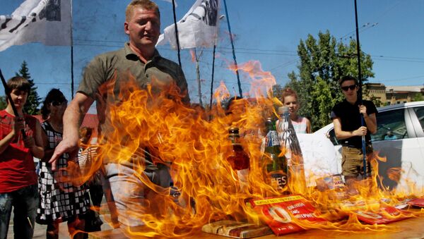 Participants of a protest rally against the halting of import of Ukrainian goods to Russia burn Russian goods in front of the Embassy of the Russian Federation in Kiev - Sputnik International