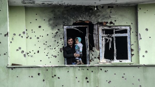 A man holding an infant stands on the balcony of a damaged house, after curfew ended in the southeastern Turkish town of Silopi on January 19, 2016 - Sputnik International