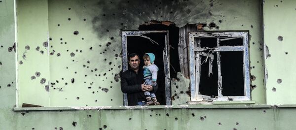 A man holding an infant stands on the balcony of a damaged house, after curfew ended in the southeastern Turkish town of Silopi on January 19, 2016 - Sputnik International