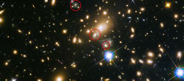 This image shows the appearances of the Refsdal supernova. The uppermost circle shows the position of the supernova as it could have been seen in 1998. The lowermost circle shows the galaxy which lensed the supernova four time — a discovery made in late 2014. The middle circle shows the latest position of the reappearing supernova in 2015. - Sputnik International