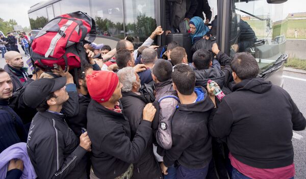 Migrants struggle to board a bus sent to pick them up on the closed highway A4 towards Vienna at the Austrian side of the border between Hungary and Austria on September 11, 2015 near Nickelsdorf, Austria. Migrants struggle to board a bus sent to pick them up on the closed highway A4 towards Vienna at the Austrian side of the border between Hungary and Austria on September 11, 2015 near Nickelsdorf, Austria. - Sputnik International