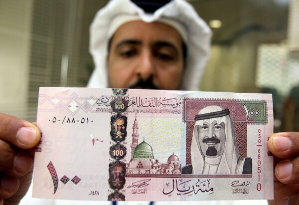 A Saudi banker displays the new one hundred riyal banknote bearing the portrait of Saudi King Abdullah bin Abdul Aziz al-Saud at a bank in Riyadh, 05 June 2007. - Sputnik International