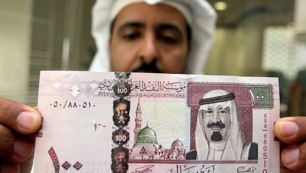 A Saudi banker displays the new one hundred riyal banknote bearing the portrait of Saudi King Abdullah bin Abdul Aziz al-Saud at a bank in Riyadh, 05 June 2007 - Sputnik International