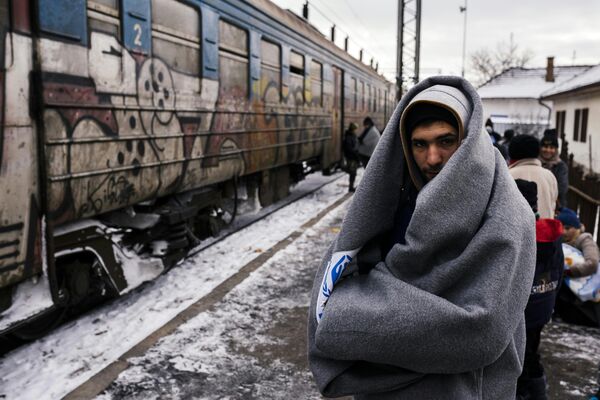 A migrant wrapped in a blanket to keep warm, waits with other migrants and refugees to board a train heading to the border with Croatia at the train station in Presevo, on January 19, 2016, after crossing the Macedonian border into Serbia A migrant wrapped in a blanket to keep warm, waits with other migrants and refugees to board a train heading to the border with Croatia at the train station in Presevo, on January 19, 2016, after crossing the Macedonian border into Serbia - Sputnik International