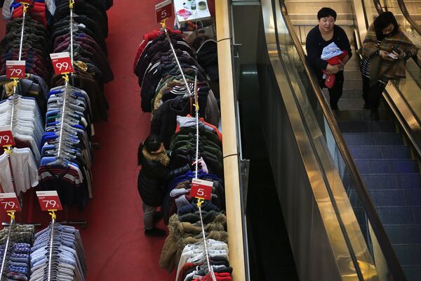 Women take an escalator near a salesperson wipes the winter clothes during a promotion sale at a shopping mall in Beijing, Wednesday, Jan. 13, 2016 Women take an escalator near a salesperson wipes the winter clothes during a promotion sale at a shopping mall in Beijing, Wednesday, Jan. 13, 2016 - Sputnik International