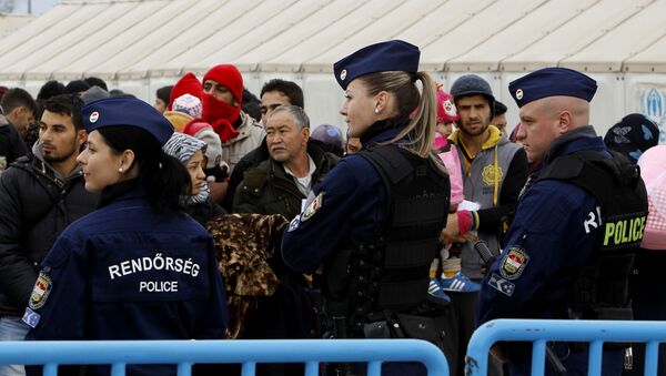 Hungarian police officers keep order as migrants wait to board a train towards Serbia. - Sputnik International