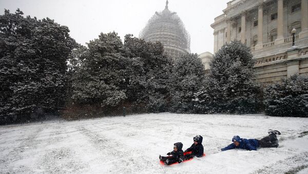 Ben Cichy slips as he pushes his sons Adrian, 18 months, and Logan 3, as they sled in the snow on Capitol Hill. - Sputnik International
