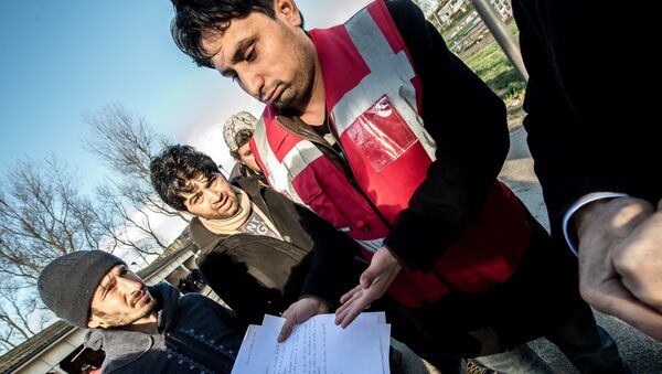 A translator shows documents to Afghan migrants during a roam by members of The French Office for the Protection of Refugees and Stateless Persons (OFPRA), at the Jules Ferry reception centre near the Jungle migrant camp in Calais, on January 14, 2016. - Sputnik International