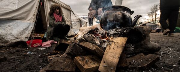 Migrants get warm around a brazier in the migrants camp of Grande-Synthe, near Dunkirk - Sputnik International