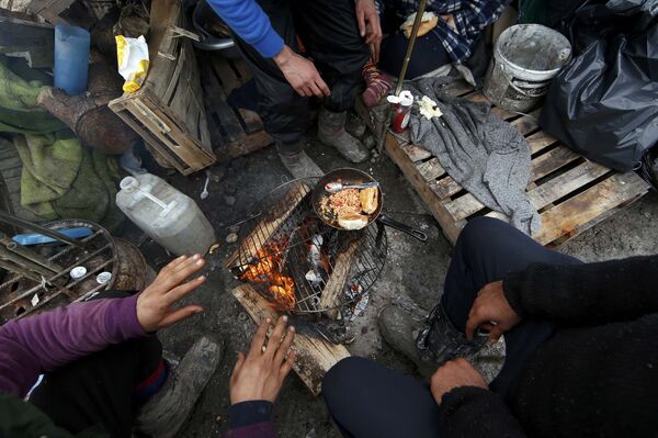 Migrants prepare their food outside shelters in a muddy field called the Grande-Synthe jungle, near Dunkirk, northern France - Sputnik International